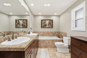 Bathroom featuring a garden tub, double vanity, and recessed lighting