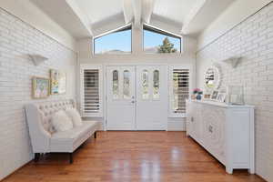 Foyer featuring brick wall, beam ceiling, and wood finished floors
