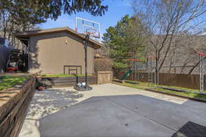 View of patio with a playground and an outbuilding