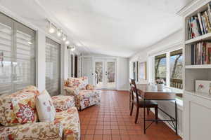 Living room featuring vaulted ceiling, dark tile patterned flooring, and french doors