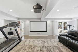 Home theater room featuring french doors, recessed lighting, a textured ceiling, light wood-type flooring, and beam ceiling