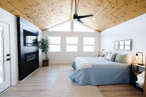 Bedroom featuring wood walls, light wood-type flooring, a ceiling fan, and wood ceiling