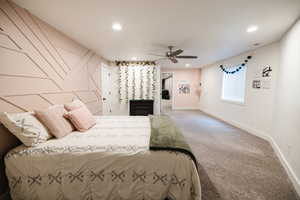 Carpeted bedroom featuring an accent wall, a ceiling fan, and recessed lighting