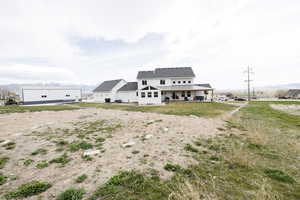 Modern farmhouse style home with a patio, a mountain view, a front yard, and roof with shingles