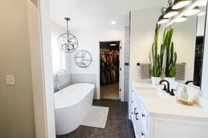 Bathroom with hanging lights, vanity, a freestanding bath, a spacious closet, and dark tile patterned flooring