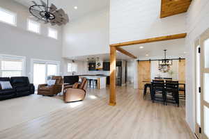 Living room featuring a barn door, healthy amount of natural light, light wood-type flooring, a high ceiling, and recessed lighting