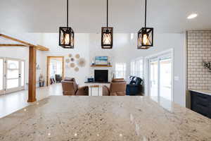 Kitchen with light stone counters, open floor plan, hanging light fixtures, and a large fireplace