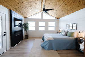 Bedroom featuring wood walls, multiple windows, light wood finished floors, ceiling fan, and wood ceiling