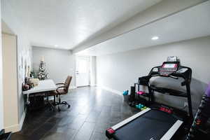 Workout room featuring a textured ceiling, dark wood finished floors, and recessed lighting