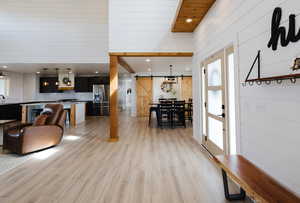 Living room with a barn door, recessed lighting, light wood finished floors, and wood walls