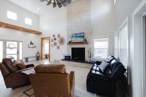 Living room with plenty of natural light, a high ceiling, wood finished floors, a stone fireplace, and wood walls