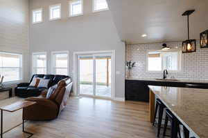 Living room featuring plenty of natural light, light wood-type flooring, and a high ceiling