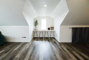 Additional living space with baseboards and dark wood-style flooring