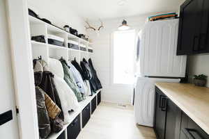 Laundry room with stacked washer and dryer, wooden walls, and cabinet space