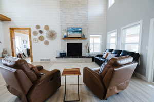 Living area with wood walls, a high ceiling, plenty of natural light, wood finished floors, and a stone fireplace