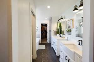 Full bath featuring a freestanding bath, two vanities, a spacious closet, recessed lighting, and dark tile patterned floors