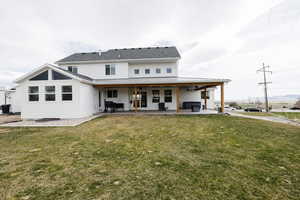 Rear view of property featuring a patio area, a ceiling fan, a yard, and a standing seam roof