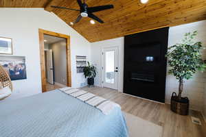 Bedroom with light wood finished floors, wooden walls, a fireplace, recessed lighting, and a ceiling fan