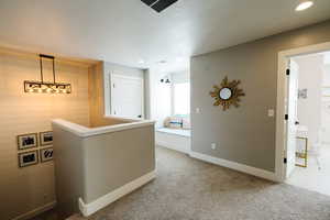 Hallway featuring light carpet, recessed lighting, and wood walls