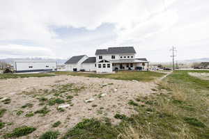 Modern farmhouse with a patio, a mountain view, a front yard, and a shingled roof