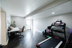 Exercise area with a textured ceiling and dark wood-style floors