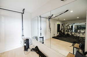 Exercise area with light wood finished floors and recessed lighting