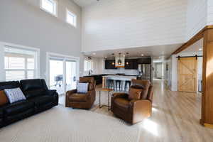 Living area featuring a barn door, a high ceiling, light wood-style flooring, wood walls, and recessed lighting