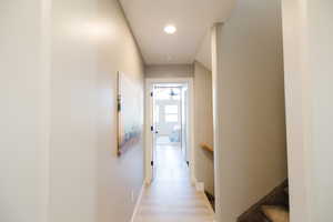 Hall with light wood-style floors, an upstairs landing, and recessed lighting