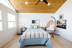 Bedroom with a vaulted wood ceiling, wood walls, light wood finished floors, and a ceiling fan