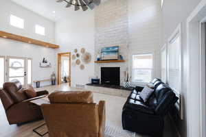 Living area featuring healthy amount of natural light, a high ceiling, wood finished floors, a fireplace, and wooden walls