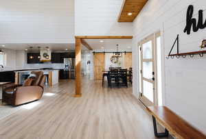 Living room featuring a barn door, recessed lighting, light wood-type flooring, and wood walls