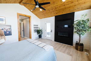 Bedroom featuring a fireplace, light wood-style flooring, recessed lighting, wooden walls, and a ceiling fan