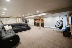 Carpeted living area with a textured ceiling, recessed lighting, and a fireplace