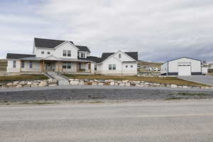 View of front of property with a porch, an outbuilding, a detached garage, and a shingled roof