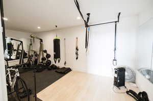 Exercise room with recessed lighting and light wood finished floors