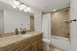 Full bathroom featuring vanity, shower / tub combo with curtain, and light tile patterned floors