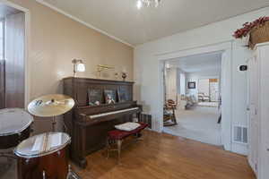 Living area with light wood-style flooring, crown molding, and wallpapered walls