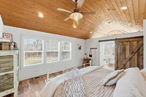 Bedroom with a barn door, wood finished floors, recessed lighting, a vaulted wooden ceiling, and ceiling fan