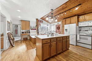Kitchen with white appliances, light wood-style flooring, light countertops, and a kitchen island