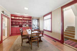 Dining area with light wood-type flooring, ornamental molding, a textured ceiling, and built in shelves