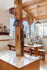 Dining room featuring a vaulted wooden ceiling, light wood-style floors, and a wainscoted wall