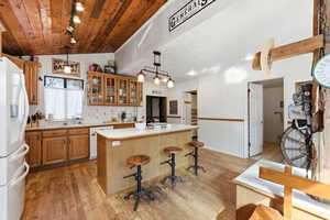Kitchen with glass fronted cabinets, light countertops, white appliances, a breakfast bar area, and a center island