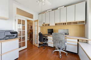 Office area with french doors, built in study area, dark wood-style flooring, and ceiling fan
