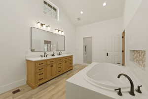 Bathroom with a garden tub, double vanity, a walk in shower, light wood finished floors, and recessed lighting