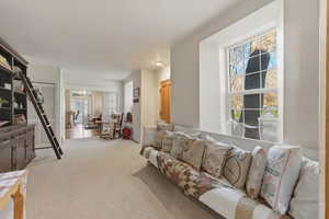 Living area with light carpet and suspended lighting