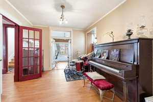 Sitting room with light wood-style flooring and ornamental molding