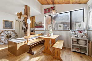 Dining space with a wainscoted wall, light wood-style flooring, ornamental molding, and a vaulted wood ceiling