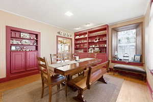 Dining area featuring built in features, light wood finished floors, and ornamental molding
