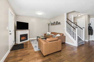 Living room featuring dark wood-type flooring and a glass covered fireplace