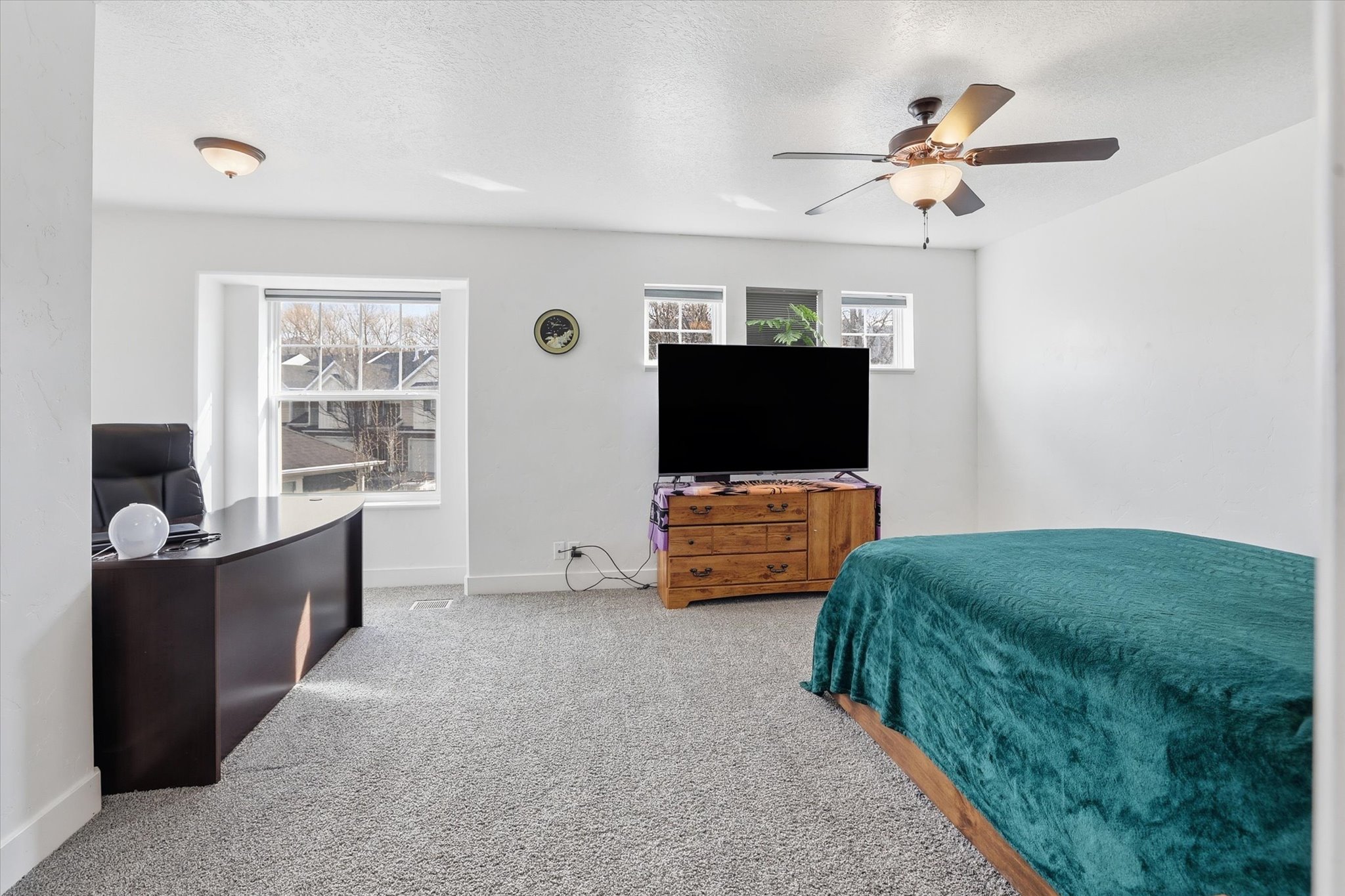 Carpeted bedroom with a ceiling fan and a textured ceiling